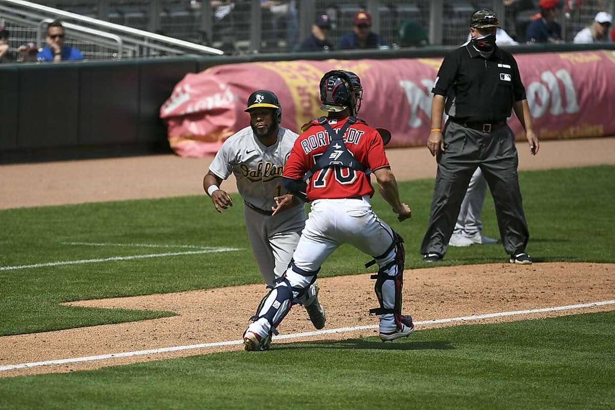 Minnesota Twins catcher Ben Rotvedt, right, makes contact with the A’s Elvis Andrus and is called for interference allowing Andrus to score during the fifth inning of Sunday’s game.