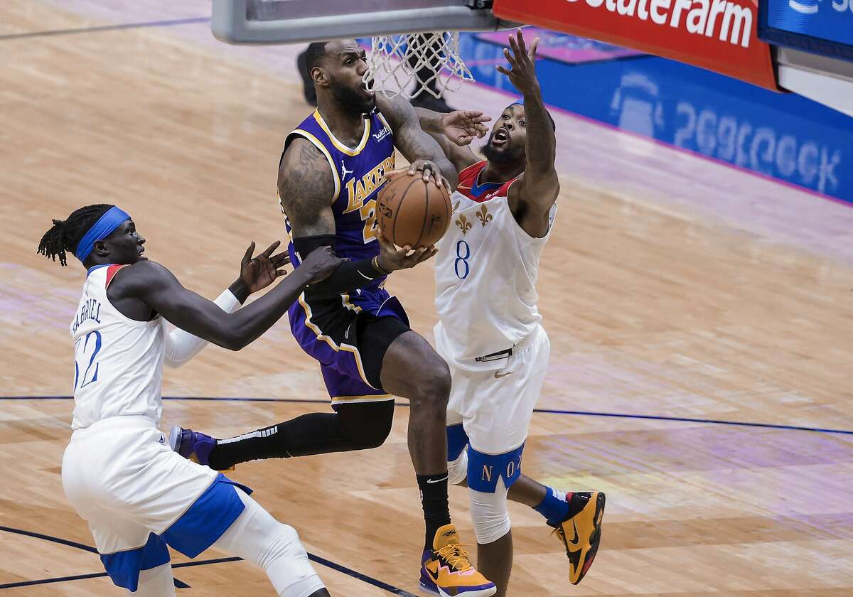 Los Angeles Lakers forward LeBron James (23) drives to the basket against New Orleans Pelicans forward Wenyen Gabriel (32) and forward Naji Marshall (8) in the second quarter of an NBA basketball game in New Orleans, Sunday, May 16, 2021. (AP Photo/Derick Hingle)