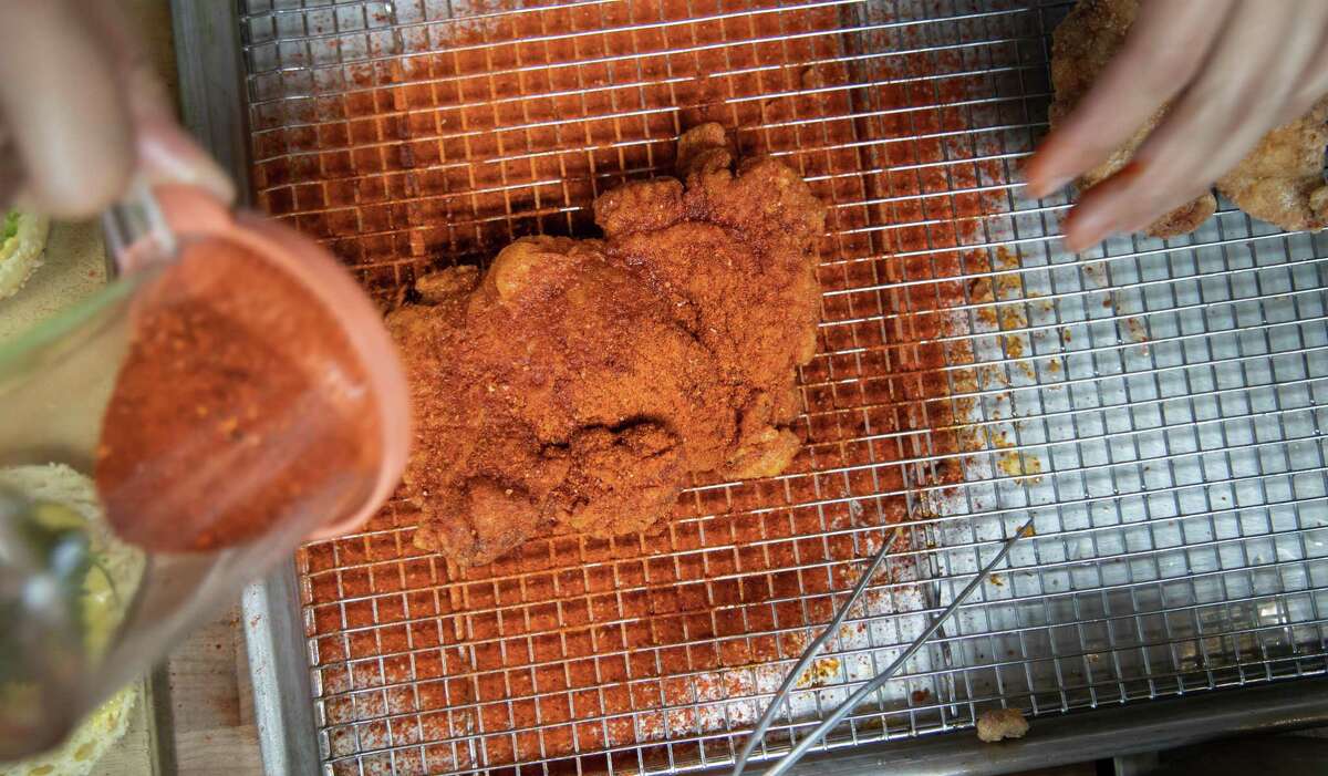 Kelvin Choy shakes a spice mix over fried chicken for Ok’s Deli’s Sichuan hot chicken sandwich.