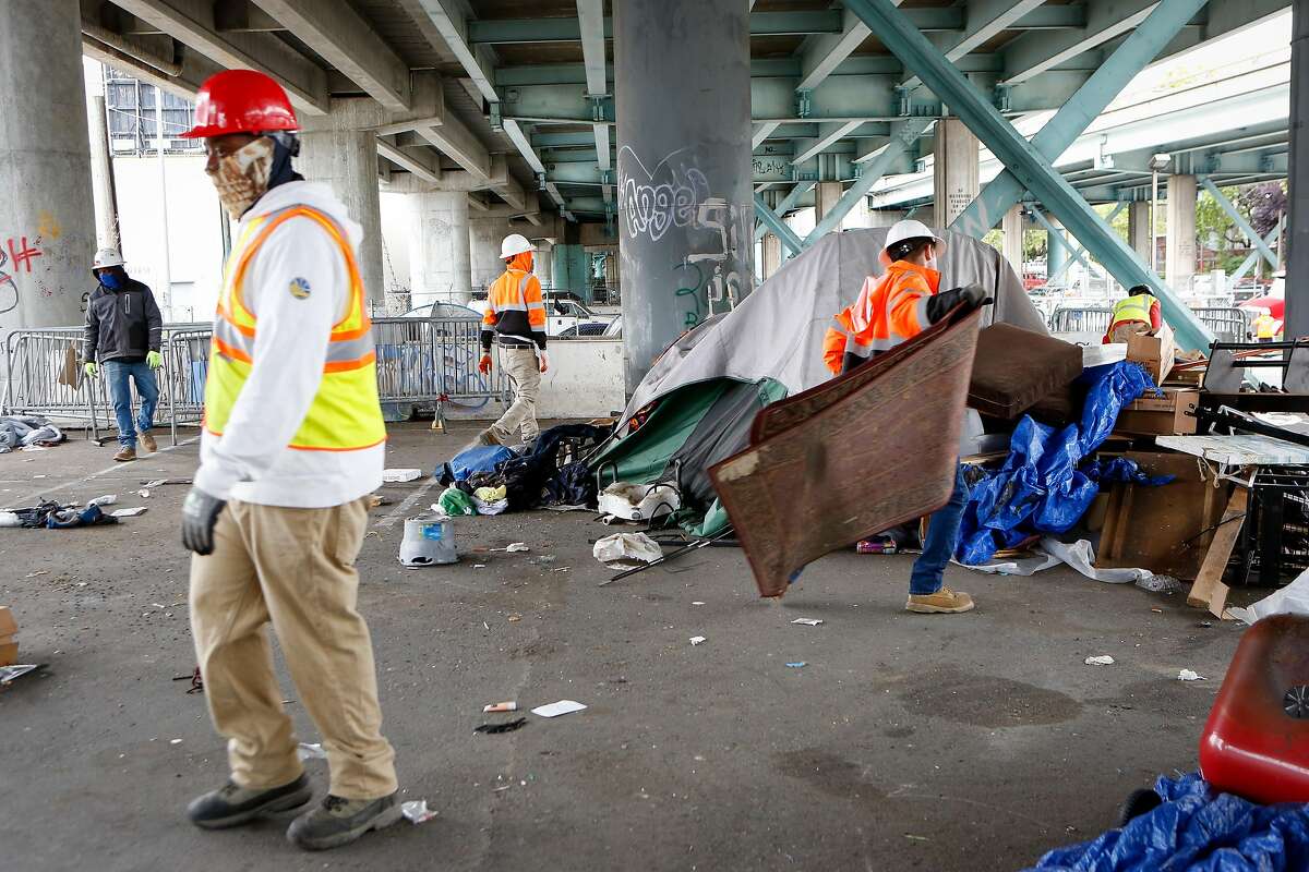 Workers from CalTrans clear items at the Merlin Street encampment just before a sweep performed by California Highway Patrol and CalTrans on Monday, May 17, 2021 in San Francisco, Calif.