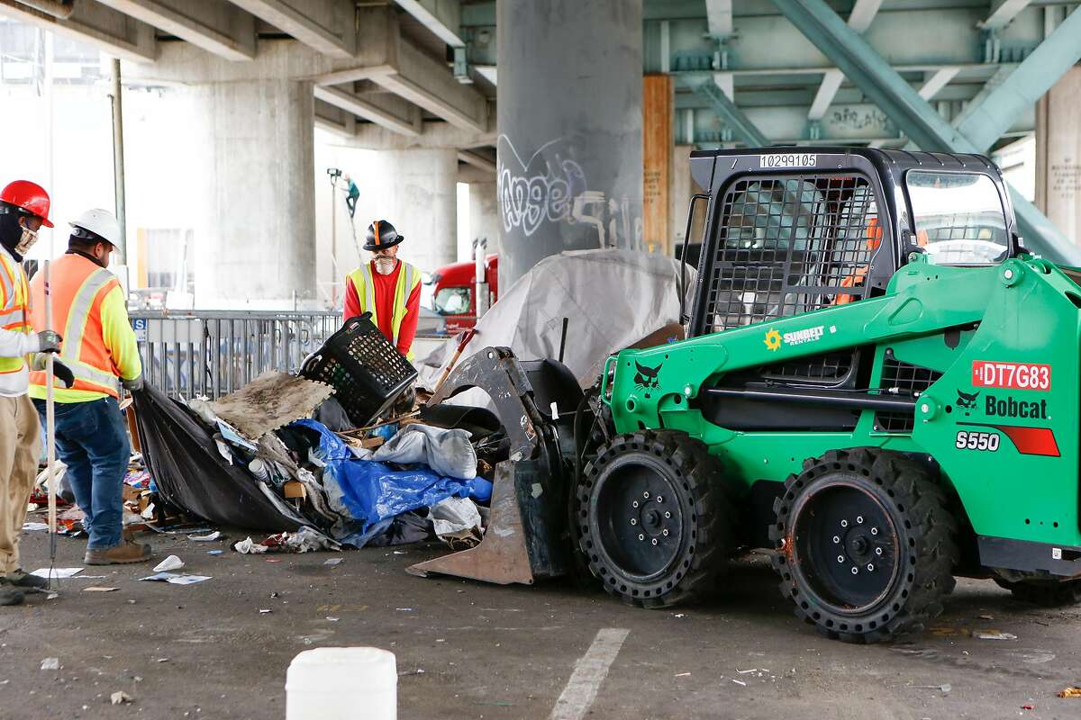 Workers from CalTrans clear items with the help of a front end loader at the Merlin Street encampment just before a sweep performed by California Highway Patrol and CalTrans on Monday, May 17, 2021 in San Francisco, Calif.