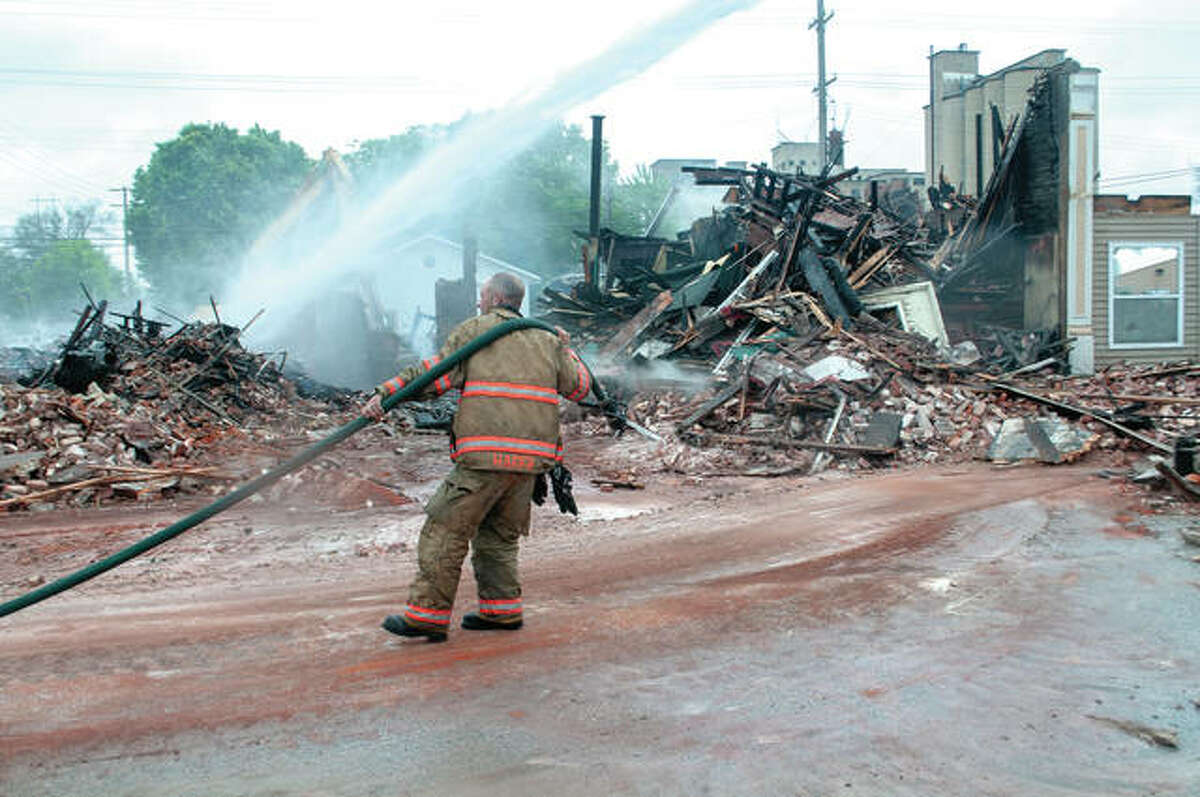 Brandon Hager, assistant fire chief for Beardstown Fire Department, drags a hose Monday while working to ensure a blaze didn’t flare up as crews were working to demolish the building at 601 E. Fourth St. Several crews were called out Sunday evening by reports of fire and smoke. The cause of the fire has not been determined.