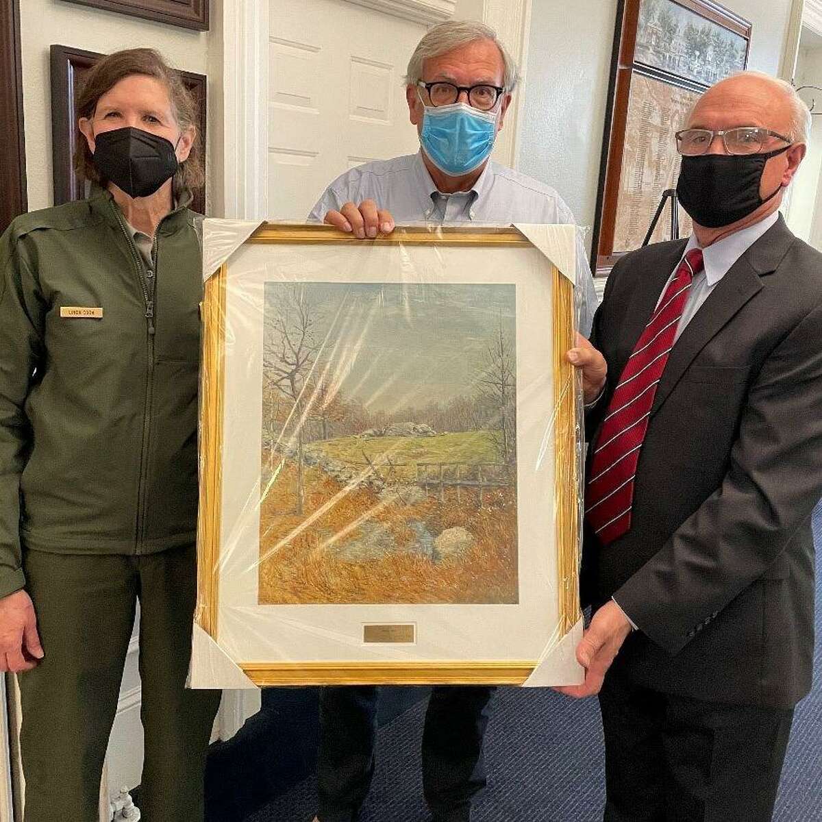 Weir Farm National Historic Park Superintendent Linda Cook and Weir Farm Art Alliance President Bob Trainer present First Selectman Rudy Marconi with a reproduction of Julian Alden Weir’s painting “Autumn” to hang in Town Hall.