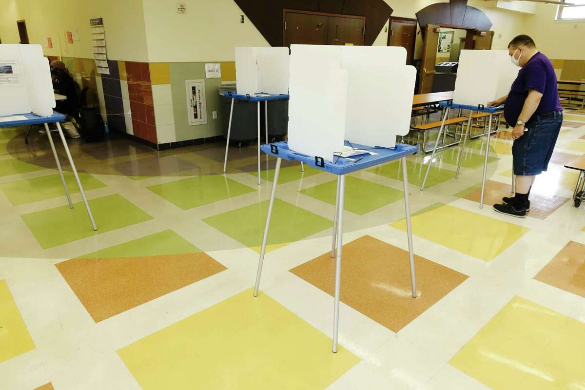 A poll worker cleans one of the voting booths at William S. Hackett Middle School for the school budget vote on Tuesday, May 18, 2021, in Albany, N.Y. (Paul Buckowski/Times Union)