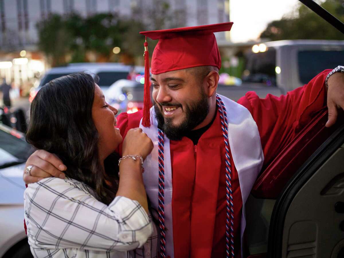 Christopher Romero, 36, hugs his wife JoAnn Romero, 30, as he celebrates his graduation from San Antonio College in a parade through campus Nov. 21. The Aspen Institute on Tuesday named SAC the top community college in the country.