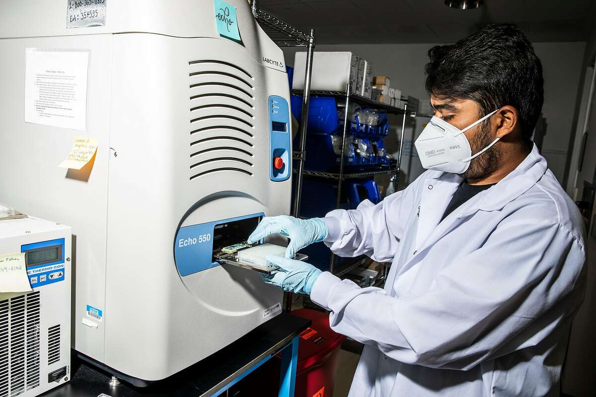 Karan Bhatt, a research associate at Chan Zuckerberg Biohub, places a bottom microplane into Echo acoustic liquid handler for genomic sequencing in San Francisco, Calif., Thursday, May 13, 2021.
