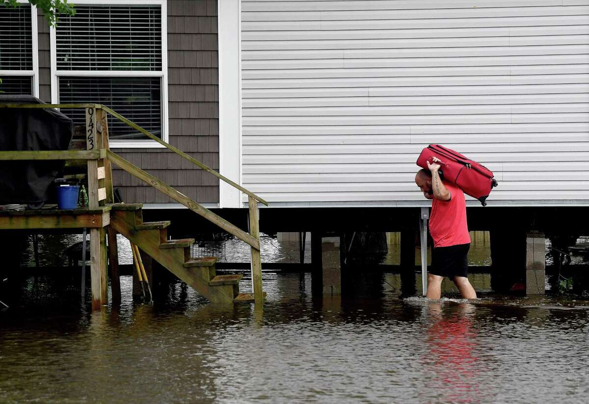 A man carries a suitcase from his vehicle parked on higher ground back through the flooded property surrounnding his home alonng FM 365 in Fannett Tuesday. The ara received over a foot of rainfall Monday, flooding area bayous and several yards and homes. Photo made Tuesday, May 18, 2021 Kim Brent/The Enterprise