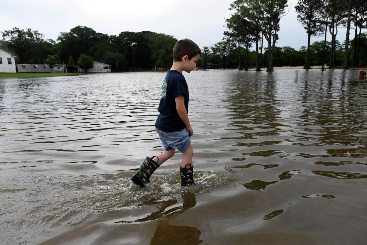 Jason Johnson walks through spillover flooding from Taylor's Bayou along LaBelle Road near Pine Tree Lodge as he and his grandfather Thomas Robin assess the conditions in Fannett Tuesday. The area received over a foot of rainfall Monday, flooding area bayous and several yards and homes. Photo made Tuesday, May 18, 2021 Kim Brent/The Enterprise