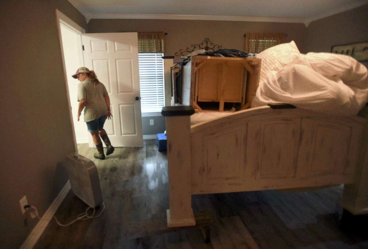 Julie Meadows walks through her bedroom toward her closet at her home on Boyt Road in Fannett Tuesday. The area received over a foot of rainfall Monday, flooding area bayous and several yards and homes, including Meadows'. This is the third time Meadows' home has flooded, and she believes a drainage ditch at the back of her property, which is overgrown and has been neglected for years, is largely to blame. Meadows was able to get her furniture up on blocks with the help of a neighbor and is hoping she can clean and dehumidify the home to prevent having to tear out floors again. Photo made Tuesday, May 18, 2021 Kim Brent/The Enterprise