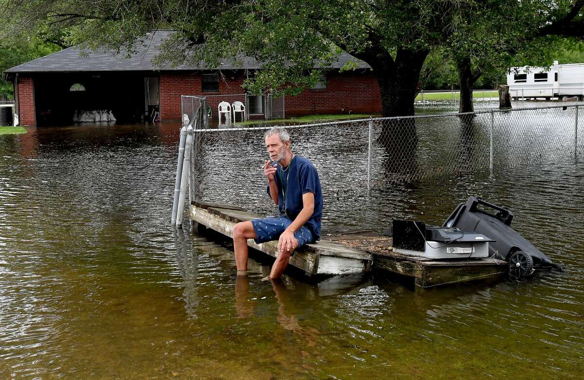 David O'Pry takes a break from removing clothing from his sister's flooded home next to his trailer in Fannett Tuesday. The area received over a foot of rainfall Monday, flooding area bayous and several yards and homes. Photo made Tuesday, May 18, 2021 Kim Brent/The Enterprise