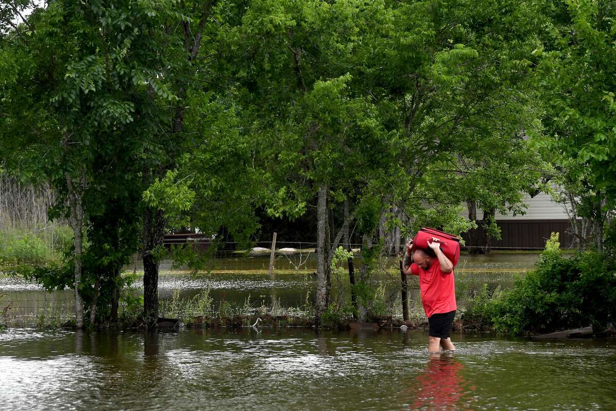 A man carries a suitcase from his vehicle parked on higher ground back through the flooded property surrounding his home alonng FM 365 in Fannett Tuesday. The ara received over a foot of rainfall Monday, flooding area bayous and several yards and homes. Photo made Tuesday, May 18, 2021 Kim Brent/The Enterprise