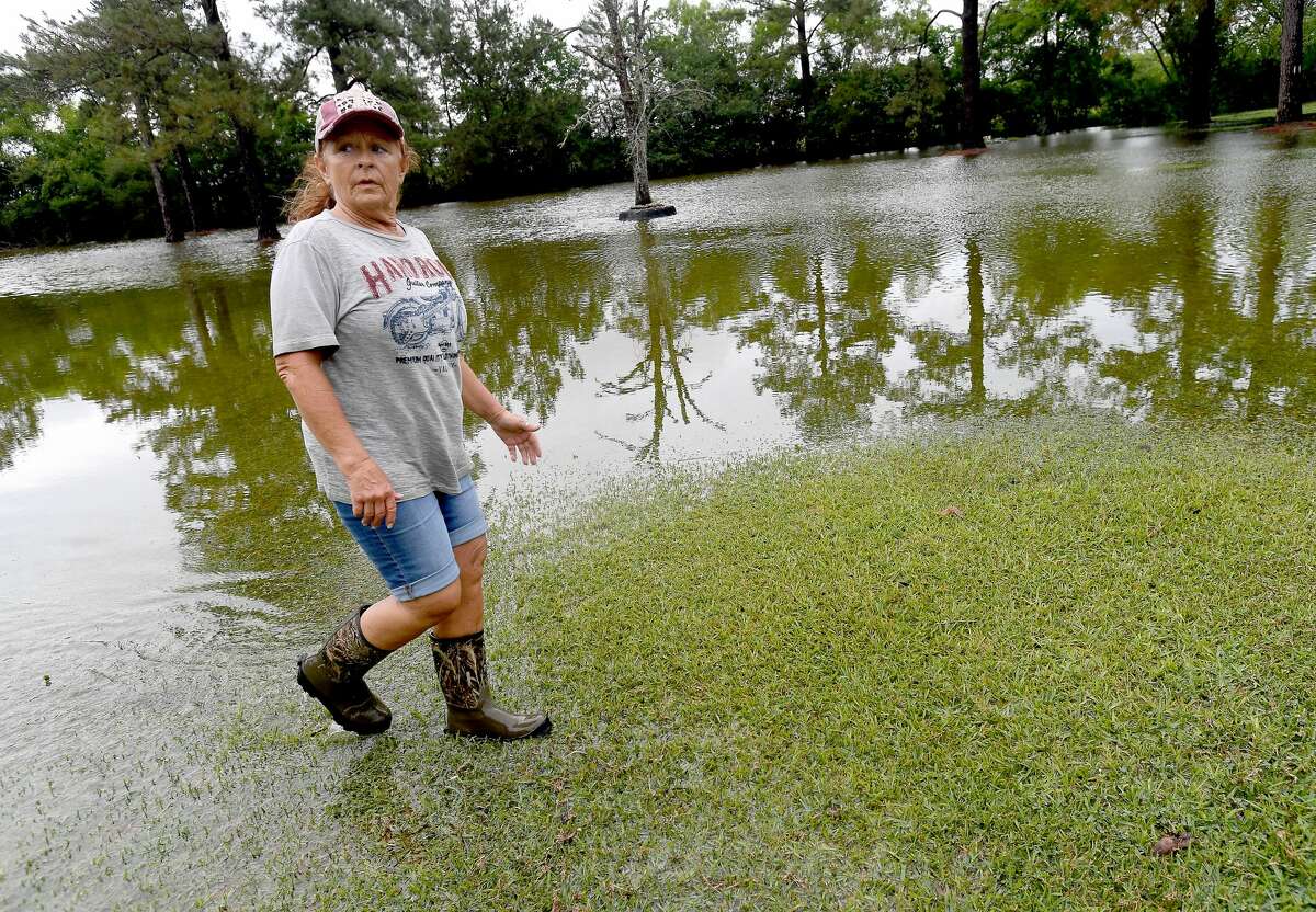 Julie Meadows walks through the flooded yard of her home on West Clubb Road in Fannett Tuesday. The area received over a foot of rainfall Monday, flooding area bayous and several yards and homes. This is the third time Meadows' home has flooded, and she believes a drainage ditch at the back of her property, which is overgrown and has been neglected for years, is largely to blame. Photo made Tuesday, May 18, 2021 Kim Brent/The Enterprise