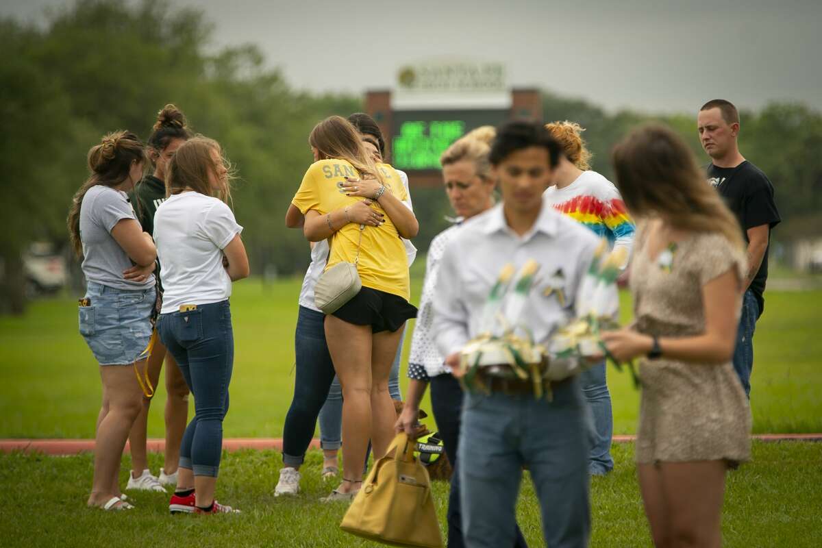 Students hug as they view the new memorial to the ten victims of the 2018 shooting at the high school, following a dedication ceremony, Tuesday, May 18, 2021, outside of the high school in Santa Fe. The Santa Fe Ten Memorial Foundation unveiled the "Unfillable Chair," a student designed memorial, on the third anniversary of the shooting. The foundation is planning a larger memorial for the future.