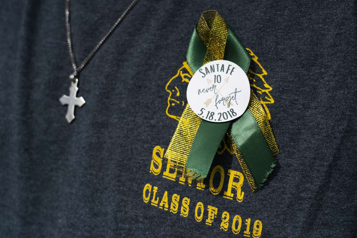 Santa Fe High School alumnus Bailey Link wears a ribbon as he visits the new memorial to the ten victims of the 2018 shooting at the high school, following a dedication ceremony, Tuesday, May 18, 2021, outside of the high school in Santa Fe. The Santa Fe Ten Memorial Foundation unveiled the "Unfillable Chair," a student designed memorial, on the third anniversary of the shooting. The foundation is planning a larger memorial for the future.