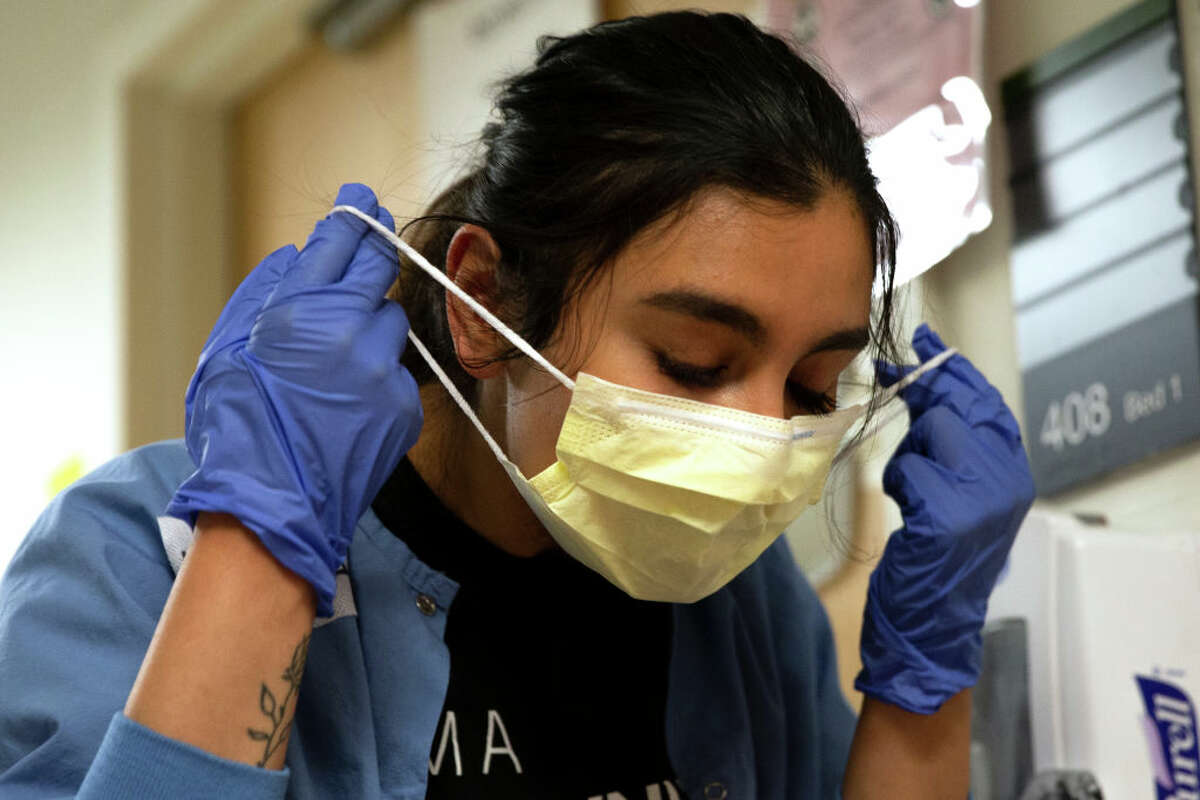 Charge nurse Liliana Palacios carefully removes her mask and PPE after tending to a patient with COVID-19 in the acute care COVID unit at Harborview Medical Center on May 7, 2020 in Seattle, Washington. 