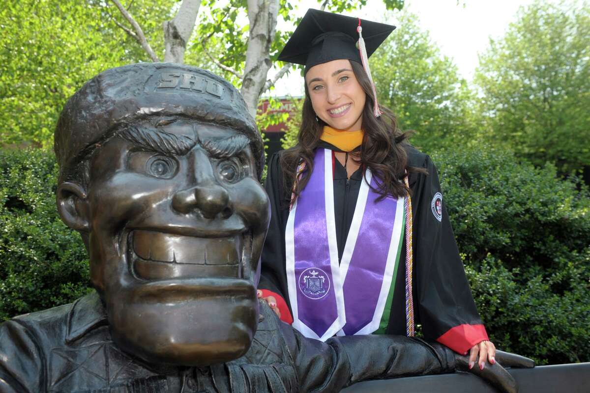 Nursing student Arianna Heonis poses next to a statue of school mascot Big Red, prior to her commencement at Sacred Heart University, in Fairfield, Conn. May 19, 2021.