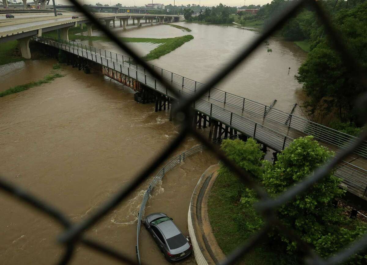 A vehicle can be seen stuck in a flooded bend of White Oak Bayou Greenway Trail, near Hogan Street on Wednesday, May 19, 2021, in Houston.