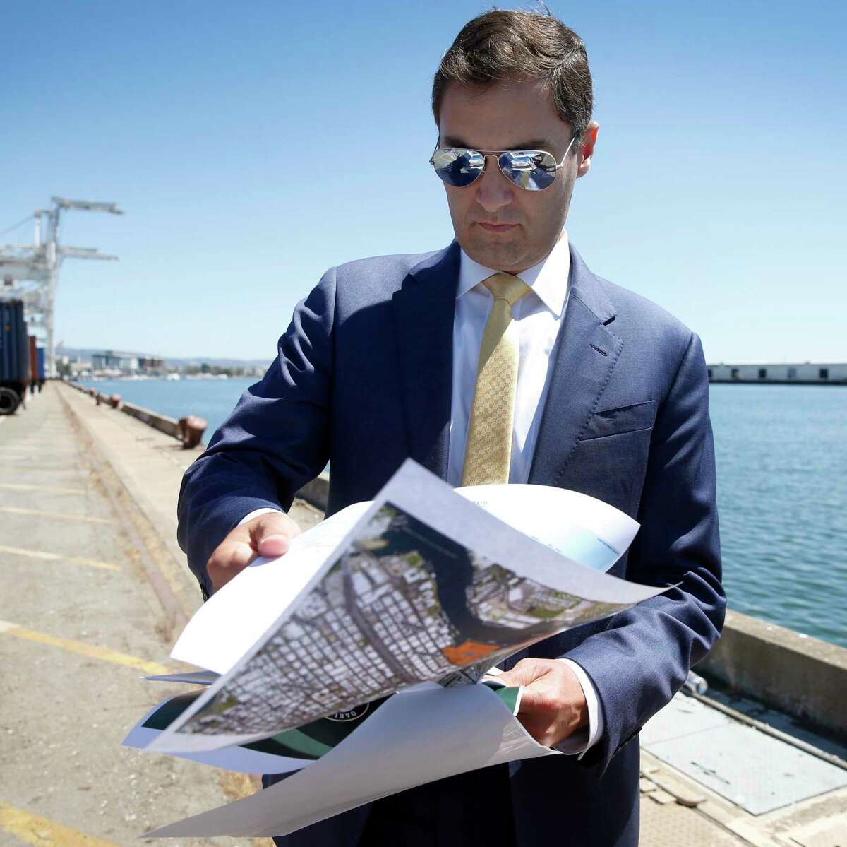 Oakland A's President Dave Kaval flips through renderings of the development plan while leading a private tour of the Howard Terminal site in Oakland, Calif. on Tuesday, Sept. 3, 2019 where the baseball team is hoping to build its new stadium.