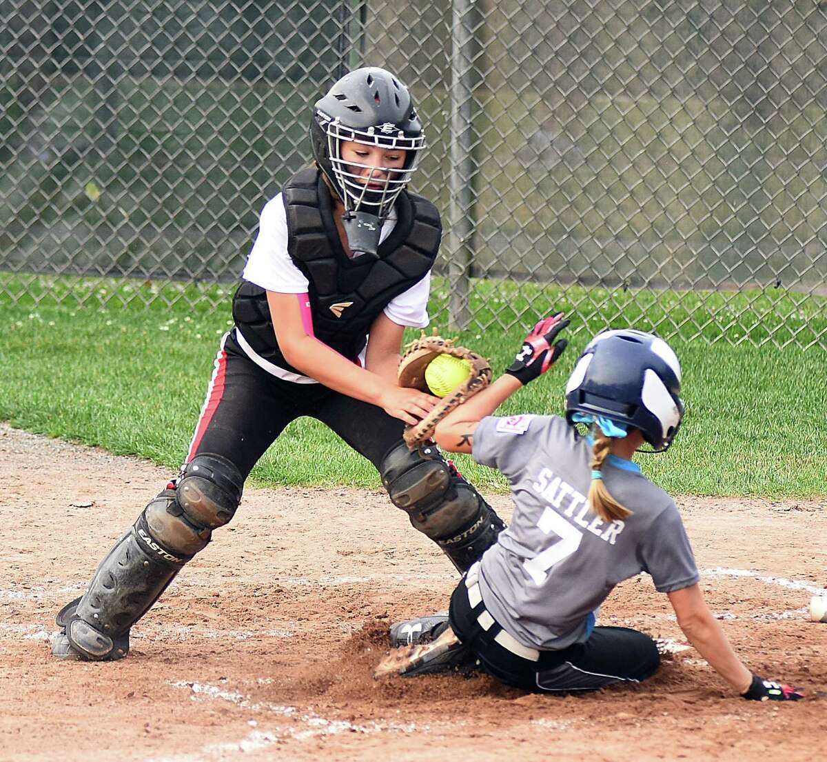Monroe catcher Kathryn Gallant, left, puts down a tag on Rowayton base runner Lilly Sattler during Friday's opening game of the Section 1 Little League 12-year-old softball tournament at Unity Park in Trumbull. Sattler was called out on the play and Monroe defeated Rowayton 13-1.