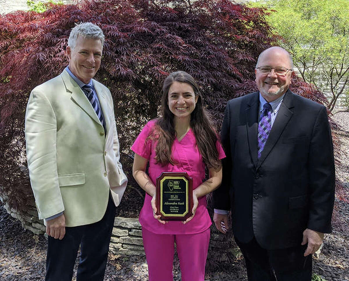 SIU SDM fourth-year student Alexandra Nash earned first-place overall and the People’s Choice Award at the 2021 Research Day. She stands holding her award with Duane Douglas, DMD, SIU SDM interim director of research, right, and SIU SDM Dean Bruce Rotter, DMD.
