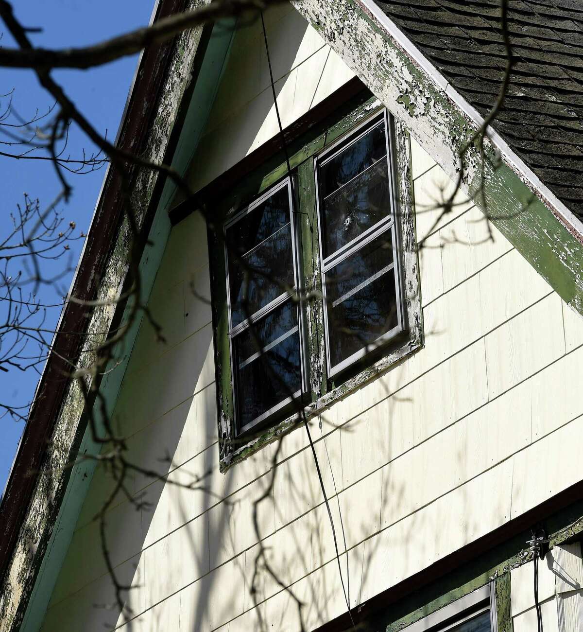 A bullet hole can be seen in the attic window of a house next door to where a shooter fired from a second-floor apartment 241 Main Street in Branford the previous day.