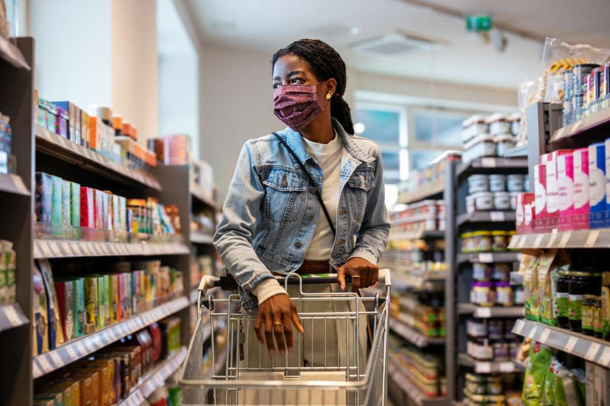 Woman wearing protective face mask buying grocery at a supermarket. 