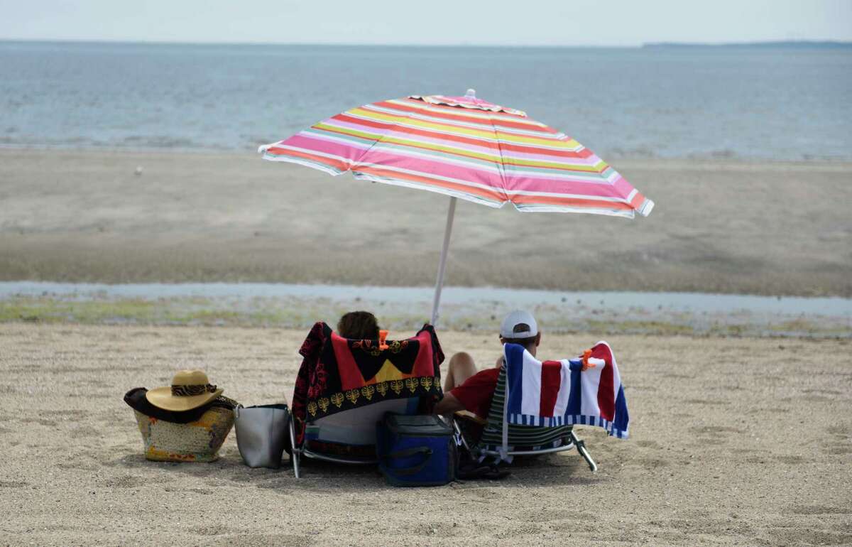 Beachgoers relax under an umbrella at the Greenwich Point Park beach in Old Greenwich, Conn. Thursday, May 20, 2021.
