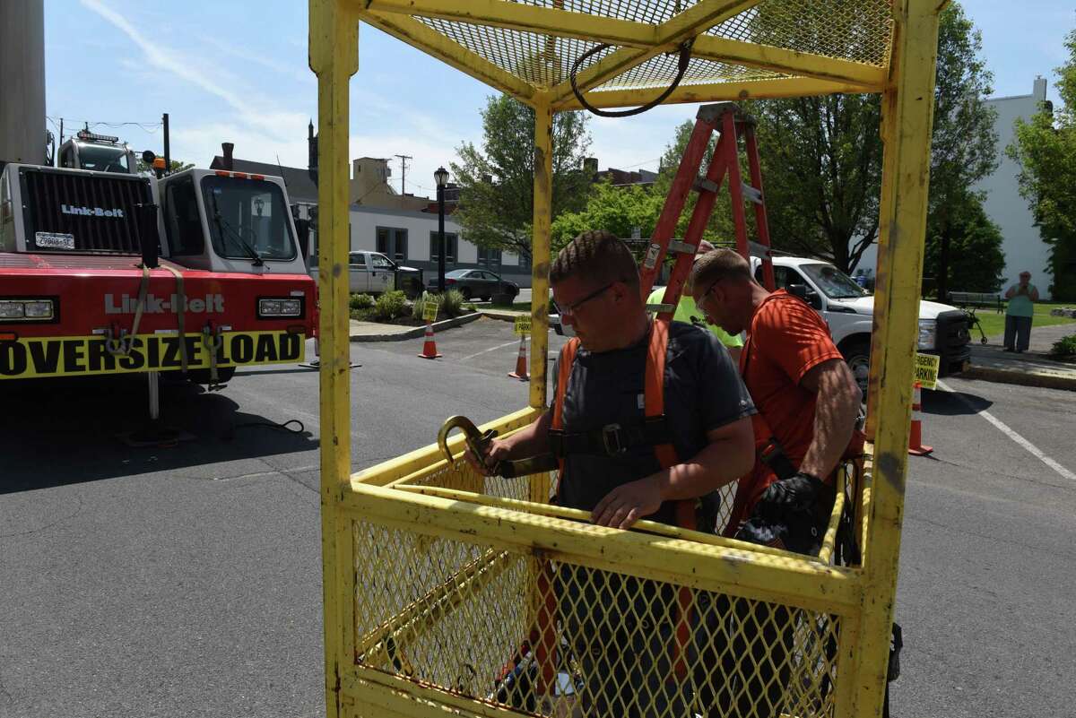 Tim Bariteau, left, and John Bonkoski, right, with the Cohoes Public Works Department climb into a crane operated work cage to lift them to the top of Cohoes City Hall for restoration work on its flagpole on Thursday, May 20, 2021, in Cohoes, N.Y. (Will Waldron/Times Union)