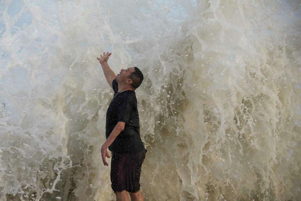 Water falls over Jimmy Villarreal, of Galveston, as a wave hits the seawall while he was watching the surf stirred up by Hurricane Laura Wednesday, Aug. 26, 2020 in Galveston.