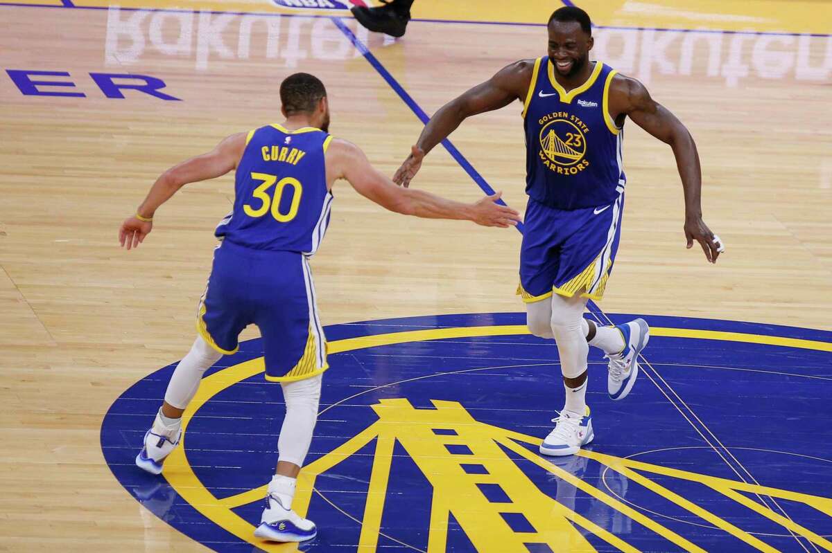 Golden State Warriors guard Stephen Curry (30) and Golden State Warriors forward Draymond Green (23) high five each other after Green’s behind-the-back pass and assist to Curry’s three-point shot in the third quarter of an NBA game at Chase Center, Saturday, May 8, 2021, in San Francisco, Calif.