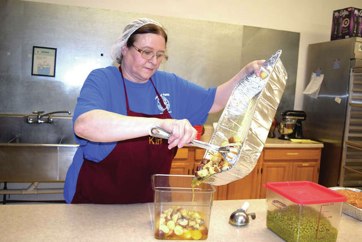 Volunteer Kim Edmonds pours leftover potatoes into a storage container Thursday after serving meals at Spirit of Faith Center. Spirit of Faith served 80 meals through the day and typically serves around 100 meals a day each Monday through Thursday. To-go meals are offered on Fridays.