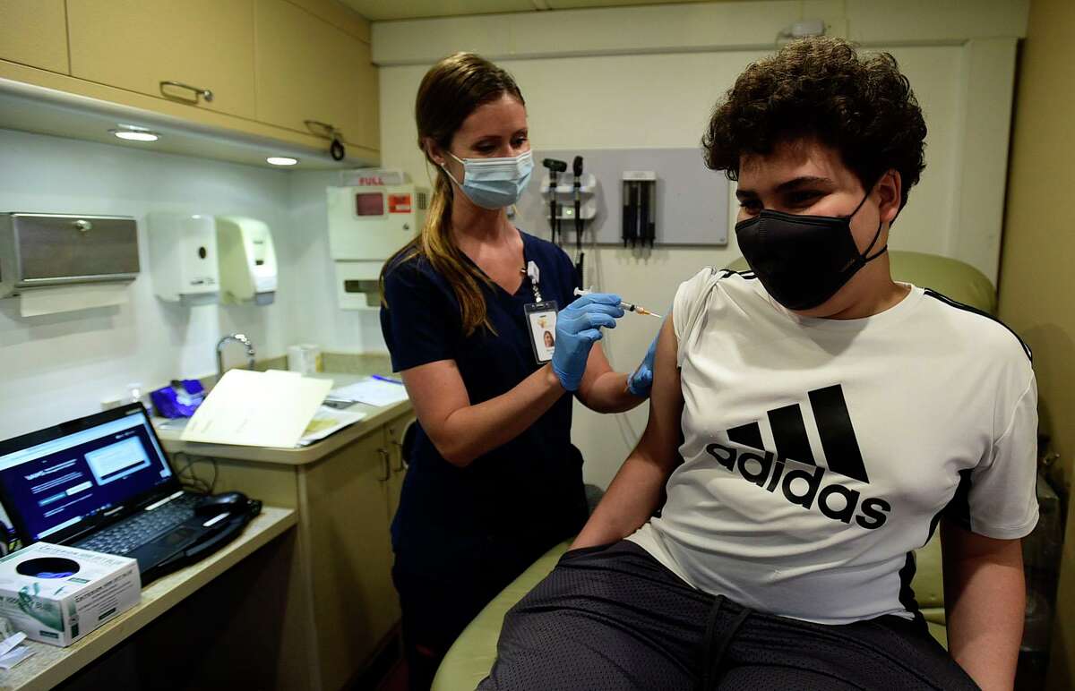 Students including West Rocks Middle School 7th grader Joniel Laldez get vaccinated by RN Elin Jokl at the Norwalk Public Schools COVID vaccine clinic Thursday, May 20, 2021, in the Norwalk Community Health Center mobile unit at West Rocks Elementary School in Norwalk, Conn.