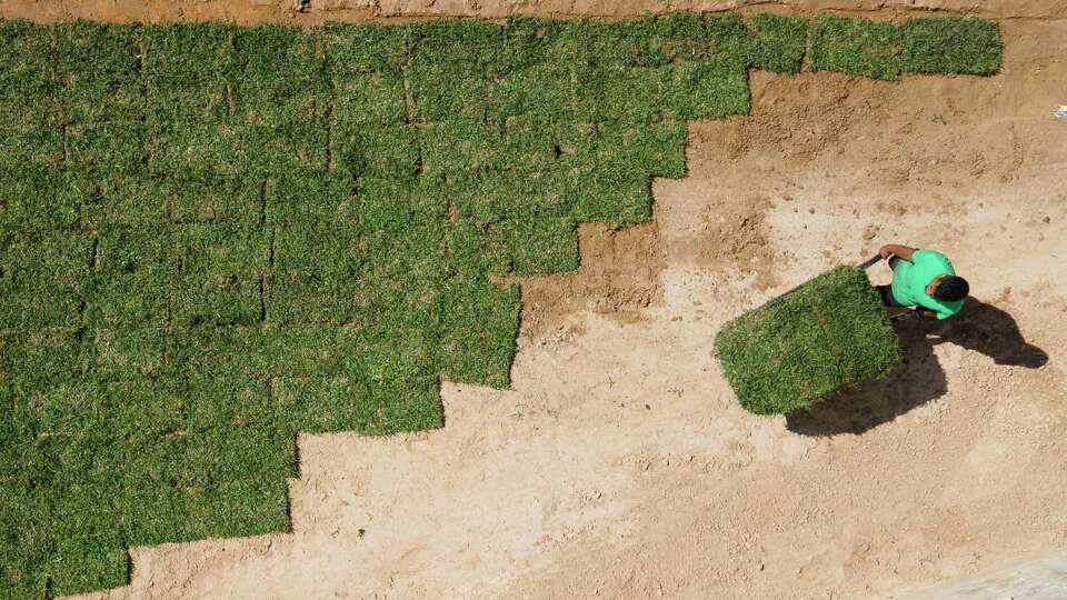 A man wheels pallets of sod between homes in a newly built neighborhood in Granger Pines, Tuesday, April 20, 2021, in Grangerland.
