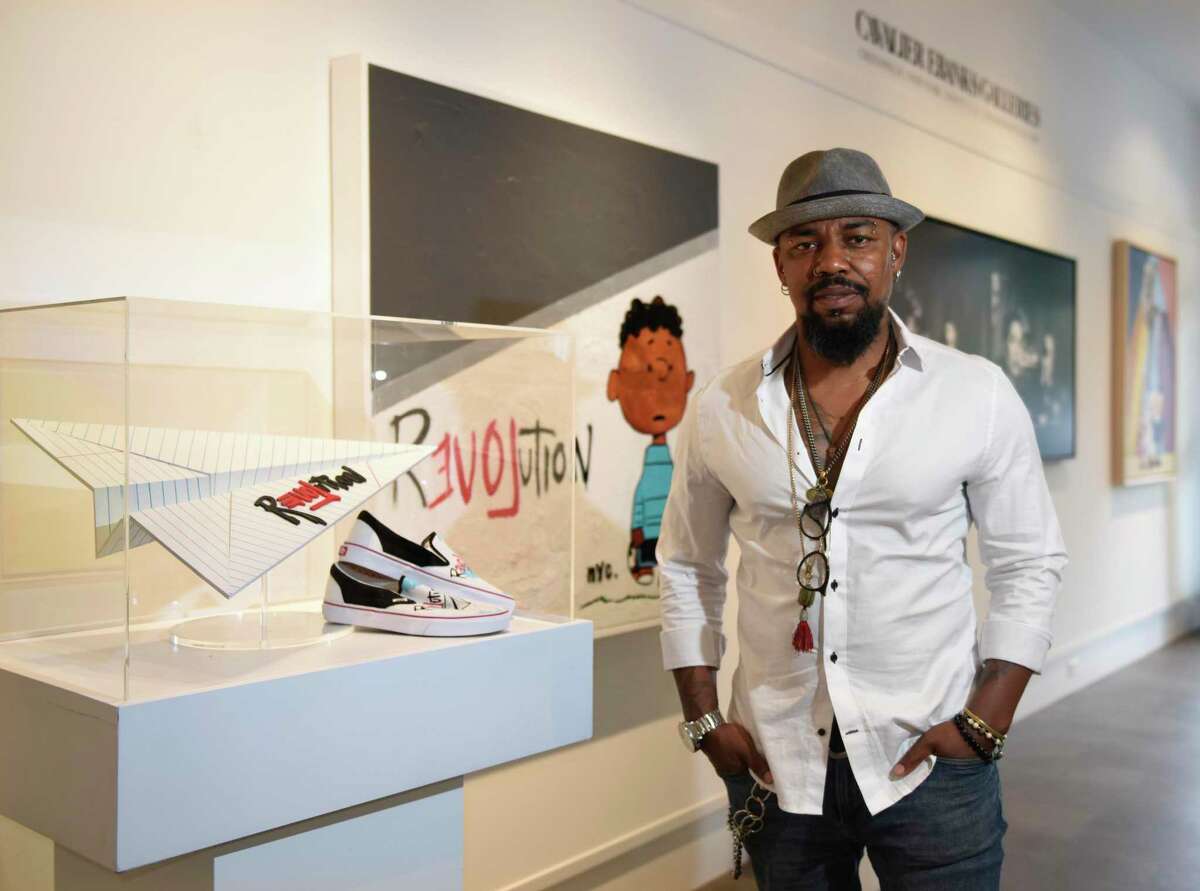Haitian-born artist Guy Stanley Philoche poses by his work displayed at Cavalier Ebanks Gallery in Greenwich, Conn. Tuesday, May 18, 2021. Philoche made headlines during the pandemic because of his efforts to raise money and purchase art works from local artists struggling because of COVID.
