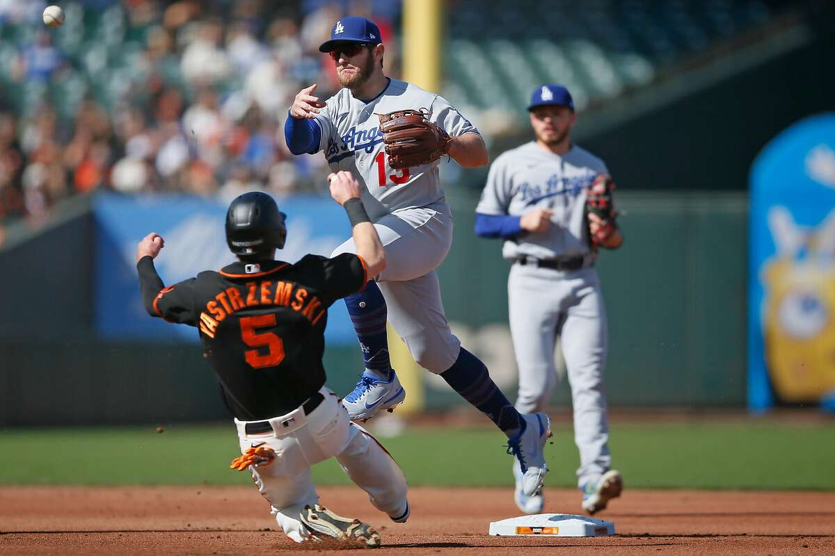 The Los Angeles Dodgers second baseman Max Muncy (13) forces out San Francisco Giants Mike Yastrzemski (5) and throws to first to force out the Giants’ Buster Posey (28) at first base for the double play in the first inning during an MLB game at Oracle Park, Saturday, May 22, 2021, in San Francisco, Calif.