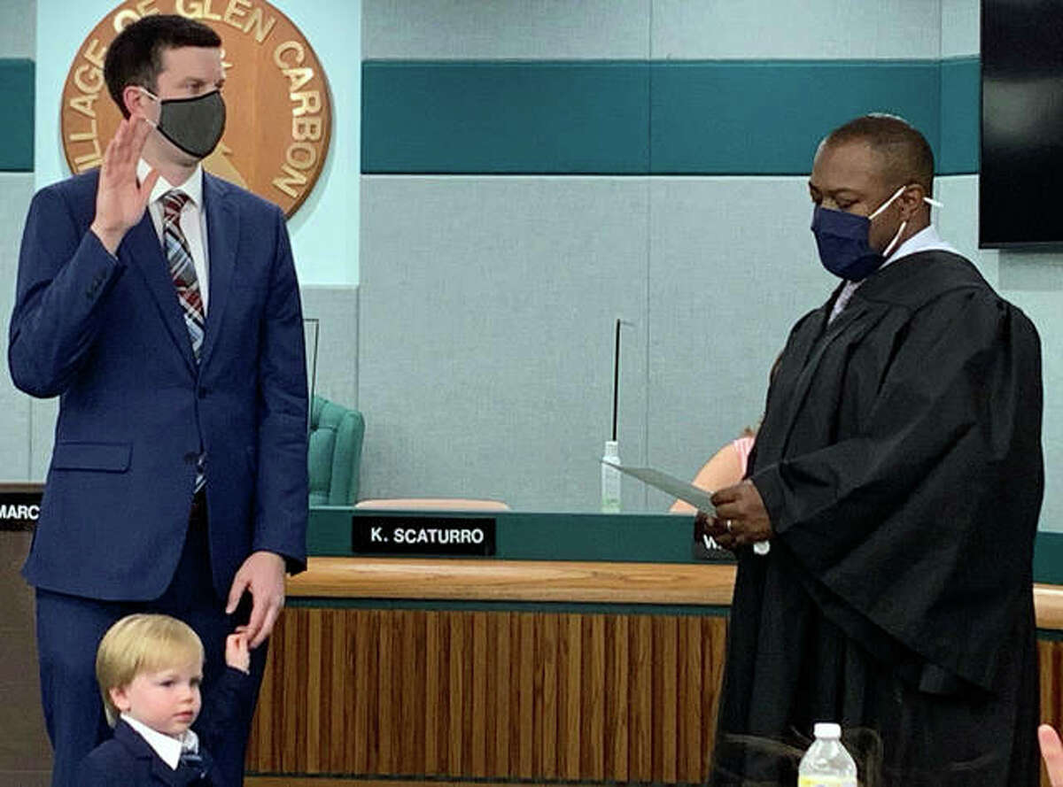 Associate Judge Ryan Jumper of the Third Circuit Court, right, swears in new Edwardsville Township Supervisor Kevin Hall while his son, Leland, looks on.