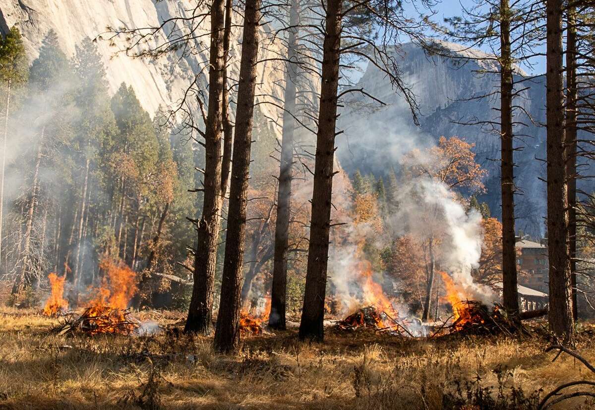 Half Dome is barely visible through the smoke from some small burn piles ignited in Ahwahnee Meadow in January 2021.