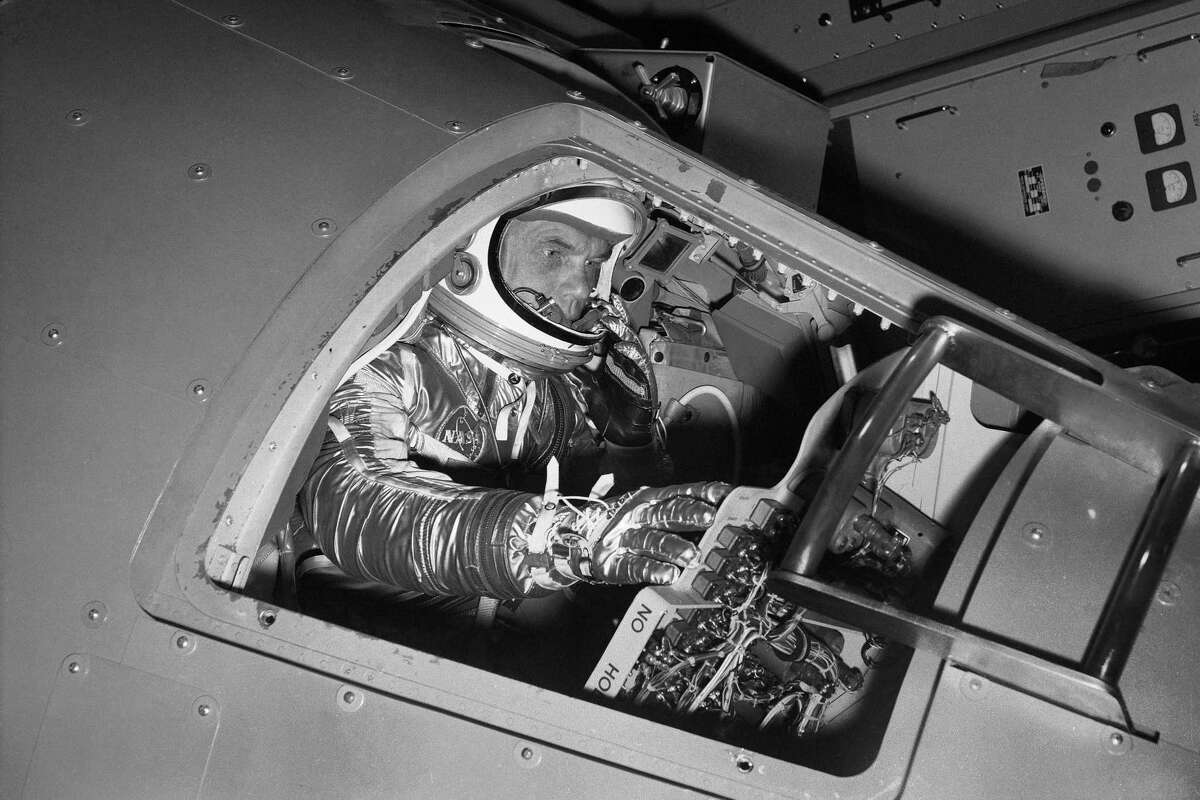 FILE - In this Jan. 11, 1961 file photo, Marine Lt. Col. John Glenn reaches for controls inside a Mercury capsule procedures trainer as he shows how the first U.S. astronaut will ride through space during a demonstration at the National Aeronautics and Space Administration Research Center in Langley Field, Va. In 2021, as more companies start selling tickets to space and the cosmos opens for travel like never before, a question looms above all others. Who gets to call themselves an astronaut?