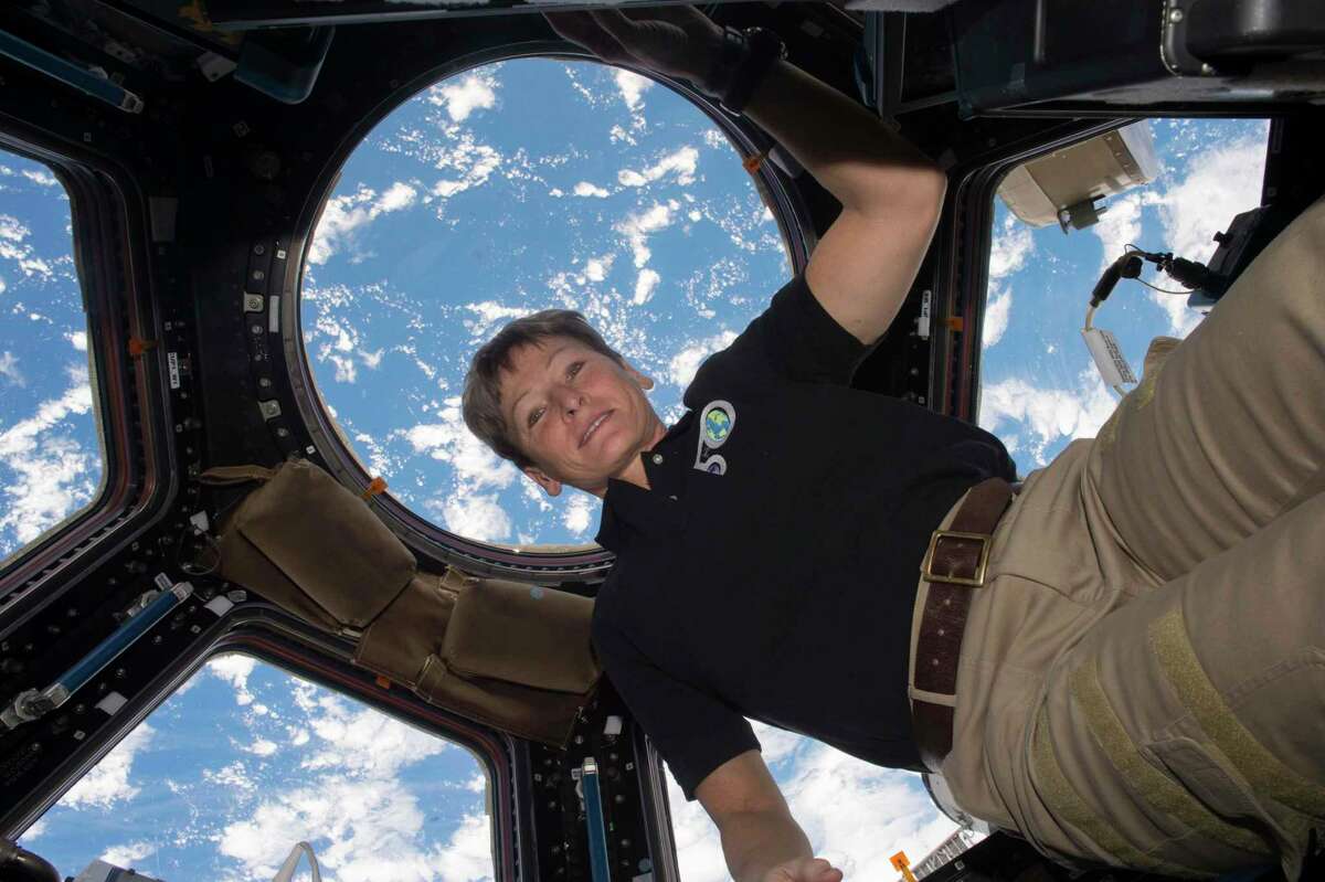 In this Dec. 3, 2016 photo made available by NASA, astronaut Peggy Whitson poses for a photo in the cupola of the International Space Station, with the Earth in the background. (NASA via AP)