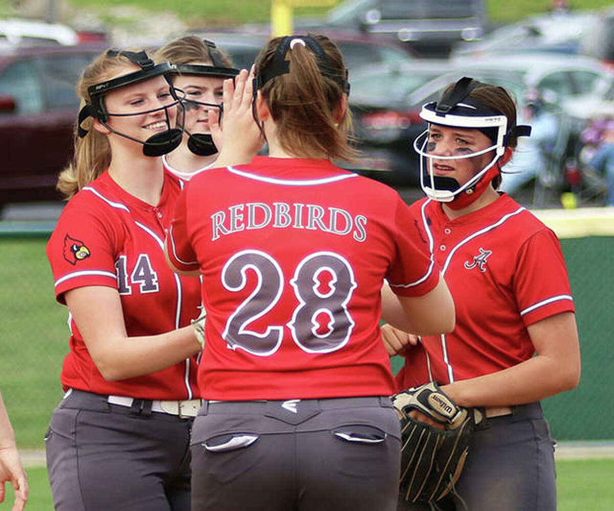 Alton pitcher Alyson Haegele (left) gets a high-five from first baseman Olivia Ducey (28) as infielders converge after a Haegele strikeout in a game earlier this season at Alton High. The Redbirds were back in Godfrey Monday and Haegele picked up a SWC win over O’Fallon.