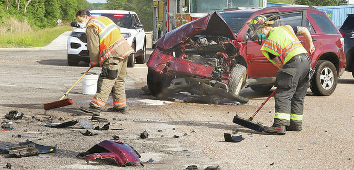 Firefighters sweep up debris left in the roadway following a collision between two Chevrolet Equinoxes Tuesday morning at the Godfrey-Alton border.