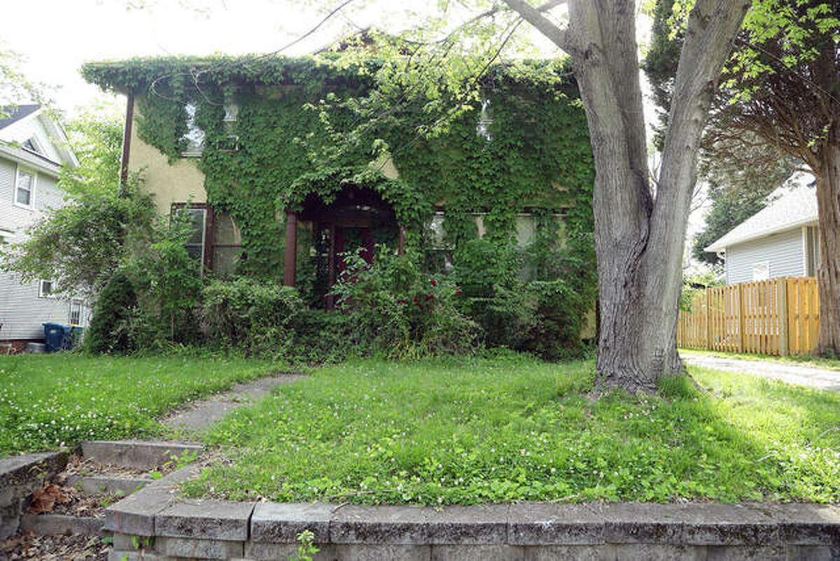 The vine-covered front of 245 Coventry Place, a long-abandoned duplex. Neighbors signed a petition to ask the city to do something about it.