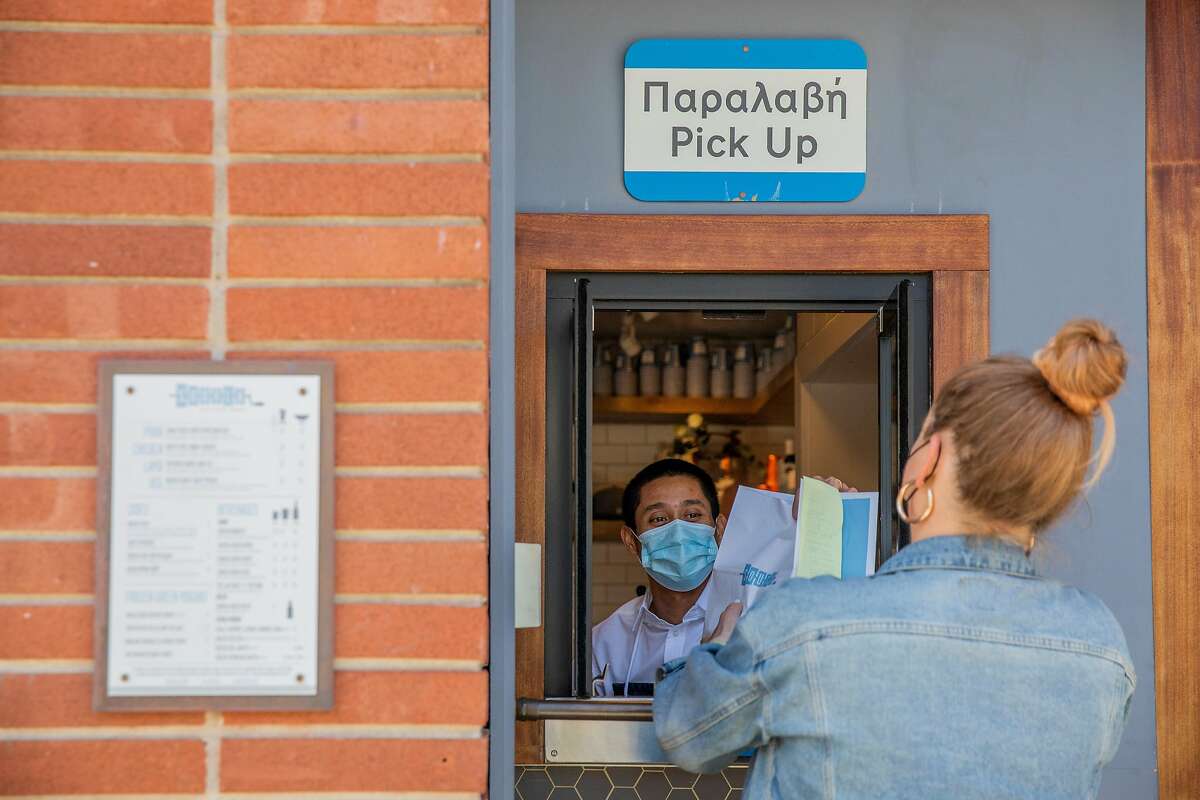 Ashley McCaffrey picks up her food order from Robert Anies at the pickup window at Souvla in S.F.