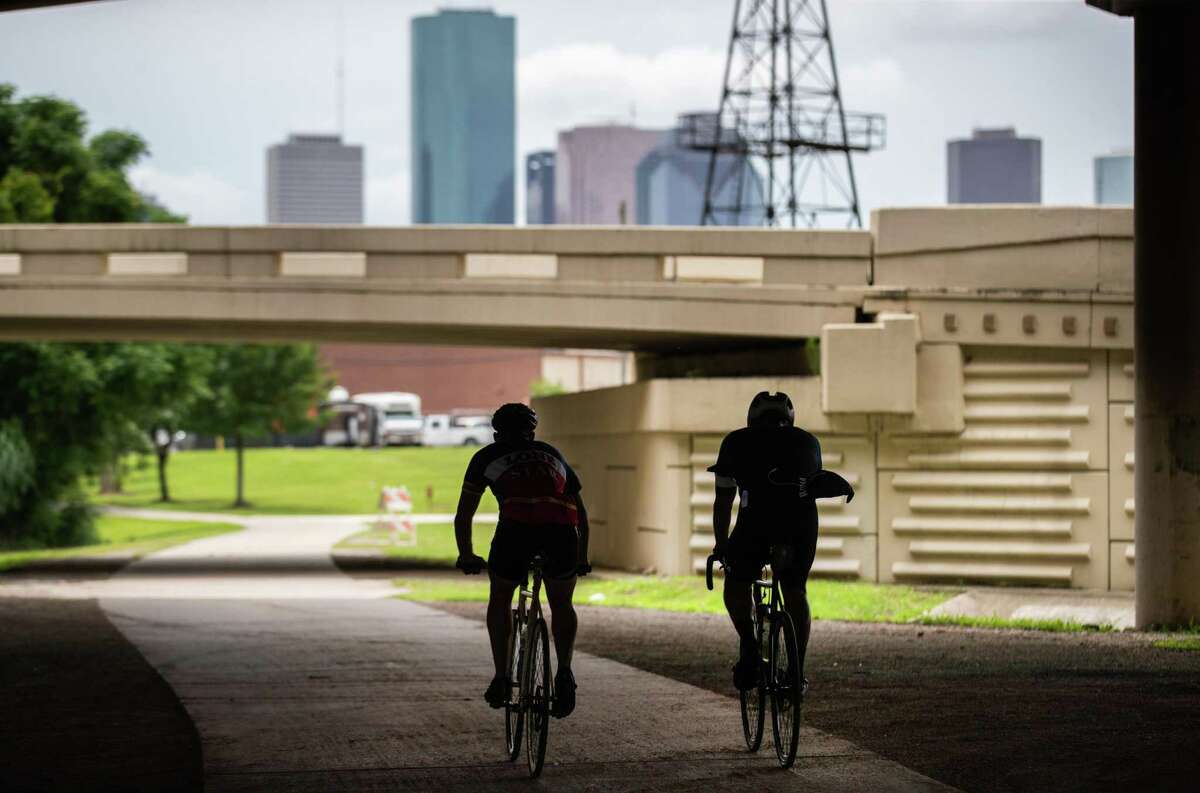 Cyclists silhouetted as they ride on the White Oak Bayou Greenway Trail, Friday, May 21, 2021, in Houston.