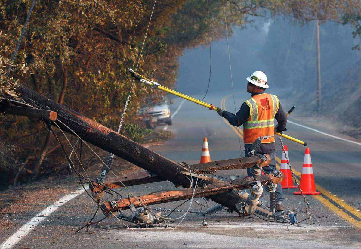 A PG&E worker cuts the power line from a fallen power pole on Geysers Road as the Kincade Fire continues to spiral out of control near Geyserville on October 26, 2019. An abandoned high voltage transmission line has been blamed for having started the forest fire.