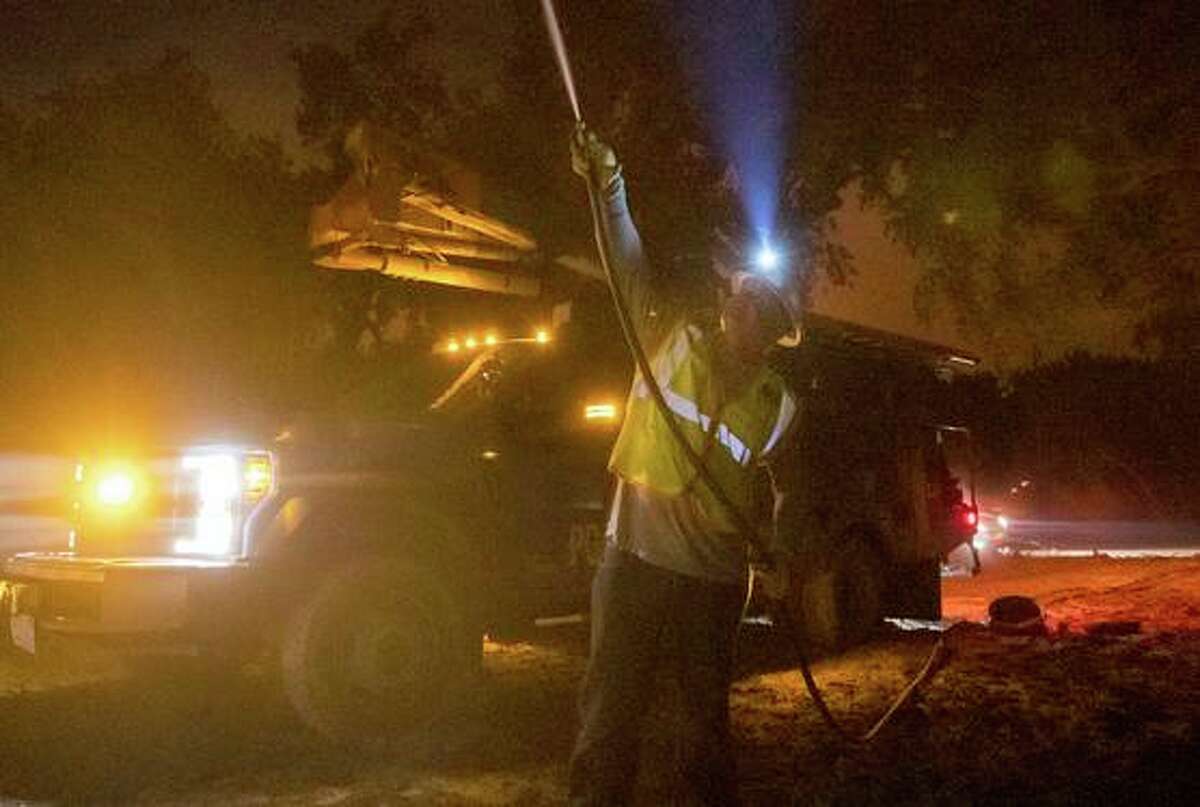 On Sept. 28, 2020, a Pacific Gas and Electric employee sprays water on a burning telephone pole at the Zogg Fire near Ono. The Shasta County district attorney says she will pursue criminal charges against the utility in connection with the fire.