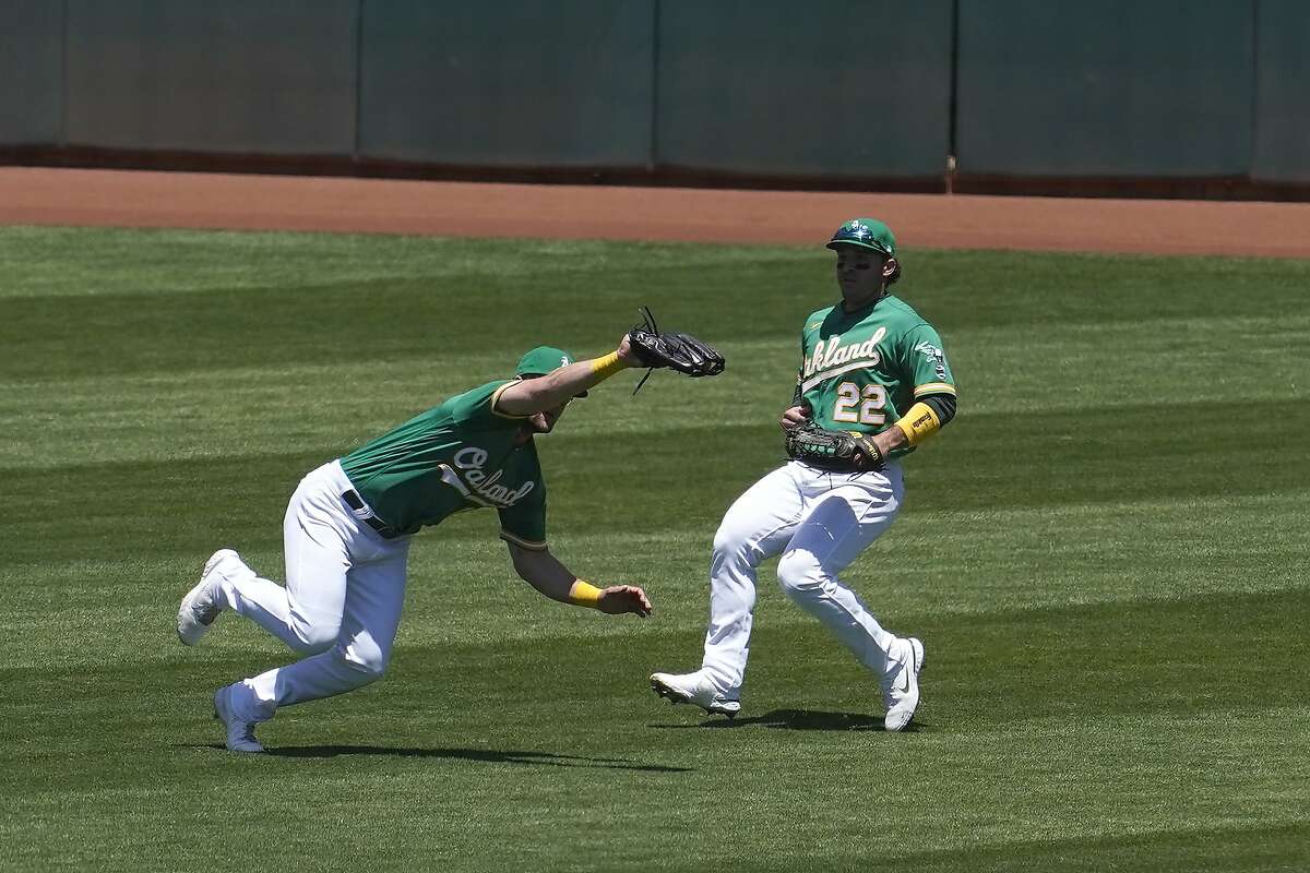 A’s left fielder Seth Brown lunges in front of center fielder Ramon Laureano to catch Jarred Kelenic’s flyball in the third.