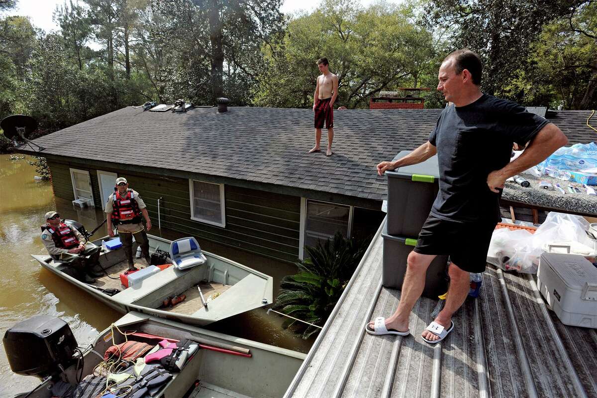 From left, Jamie Holden Sr. and Trent Black, 15, talk to Game Wardens Randy Harper, left, and Chad West from their roof in Deweyville on Wednesday. The family carried many household items and furniture to the roof to prevent evacuation. Items include a washer, dryer, microwave, 65 inch television, grill, generator and an Xbox. Photo taken Wednesday, March 16, 2016 Guiseppe Barranco/The Enterprise