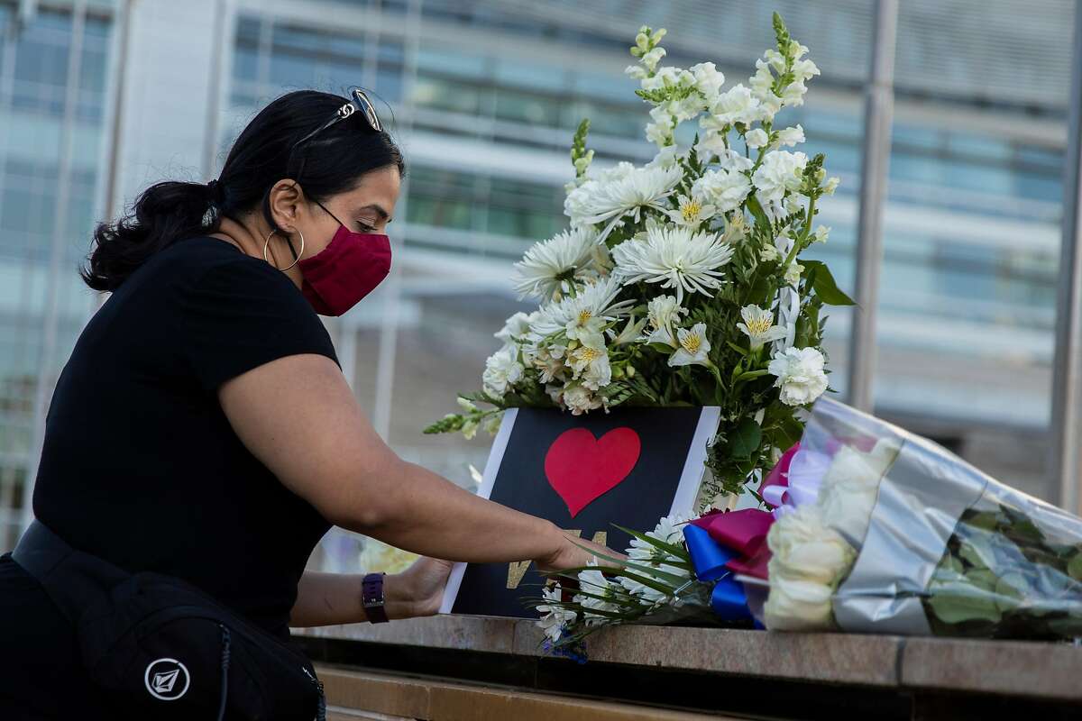 Jaspreet Kaur posts a sign at a vigil at City Hall, Wednesday, May 26, 2021, in San Jose, Calif. A shooting at the VTA Light Rail Facility yard left nine people dead, including the gunman, who was a VTA employee.