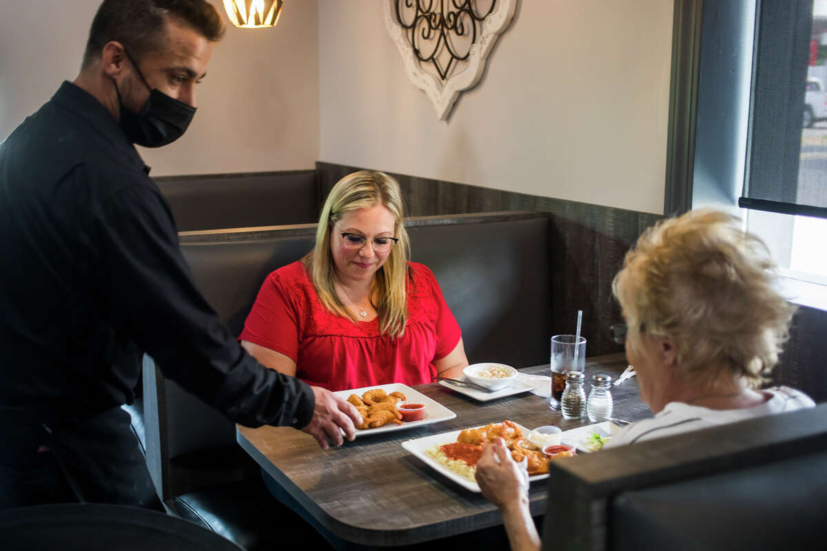 Keith Ridenour, left, serves plates of food to Vanessa Wegner, center, and Susan Downing, right, Wednesday, May 27, 2021 at Antonio's Bar and Grill, located at 1716 W. Wackerly St., the former location of Shirlene's Cuisine. (Katy Kildee/kkildee@mdn.net)
